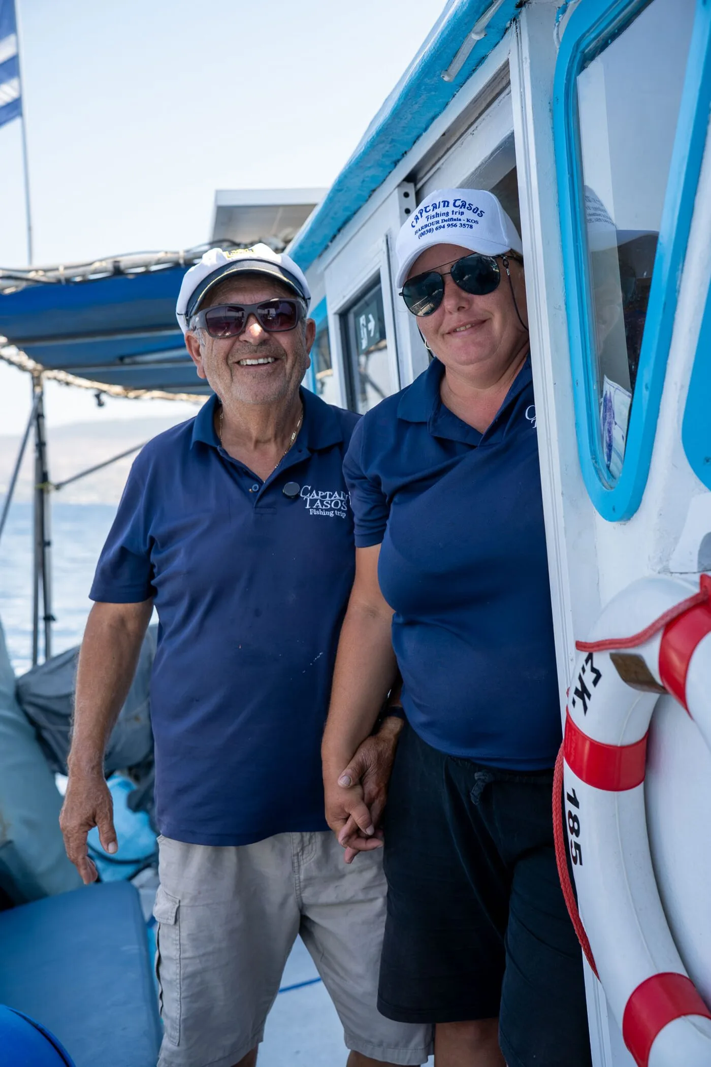 Alex and Mariana in Captain Tasos shirts on board their fishing boat in Kos