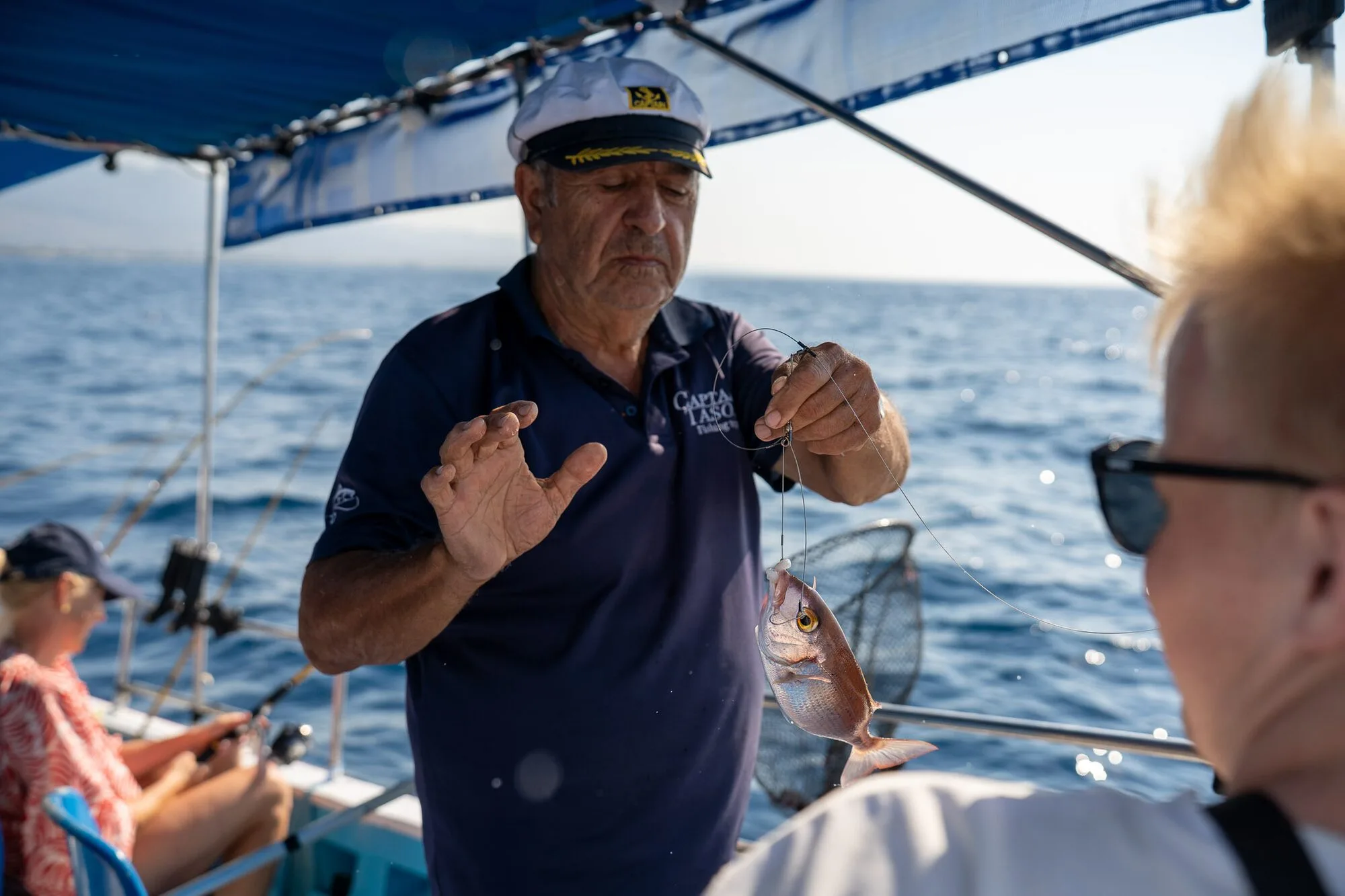 Captain Alex showing a freshly caught fish to guests on board off Kos